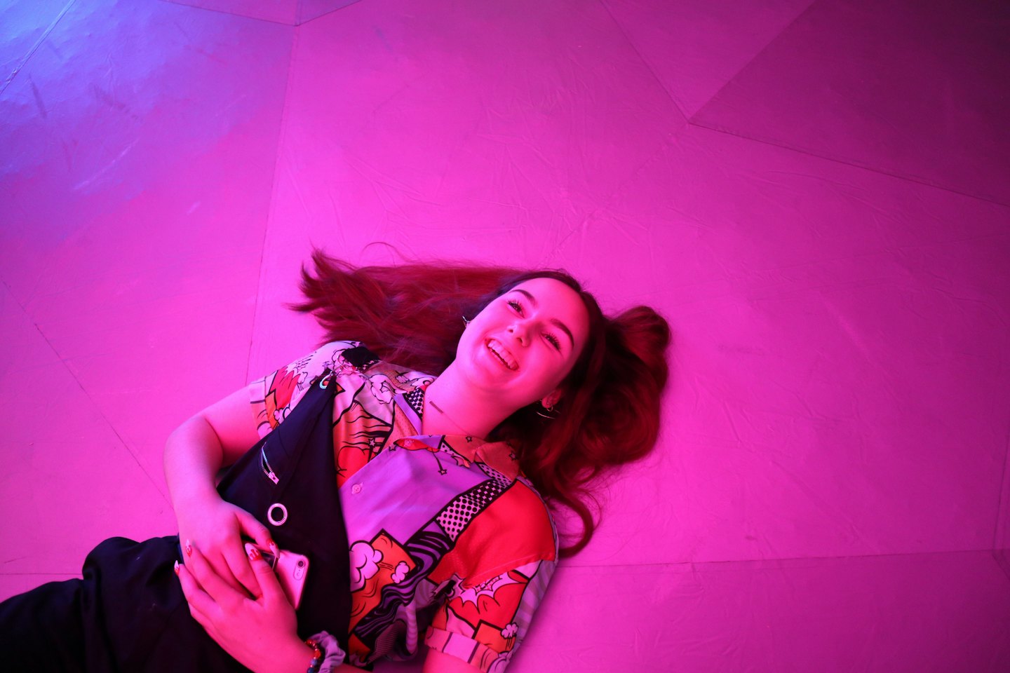 Woman lying on the floor while holding her smartphone.